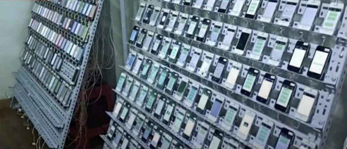 Bild aus einer Klick farm in welcher hunderte Smartphones auf Regalen aufgebaut einsatzbereit stehen